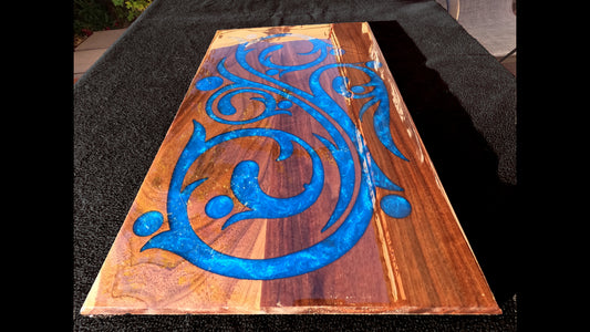 Lower front view of a blue epoxy script style inlaid into a 20X13X3/4" piece of walnut and finished with a glasslike smooth epoxy finish.