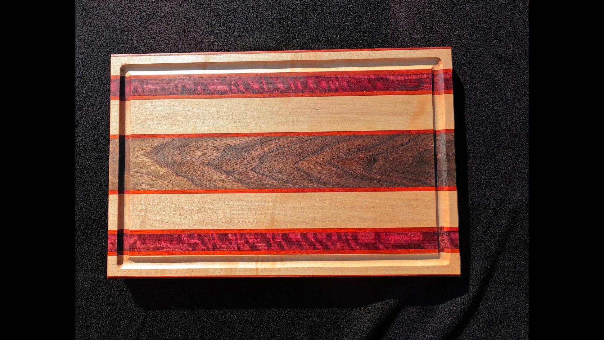 Front Top view of the Slice of life cutting board with striped pattern, featuring Maple, walnut, purple heart, and padauk hardwoods.